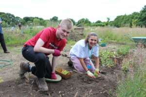 Linden and Amber plant some pansies in their plot.