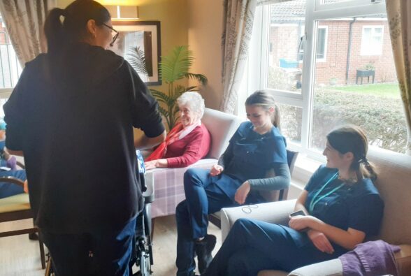 beauty therapy students sitting with an elderly resident